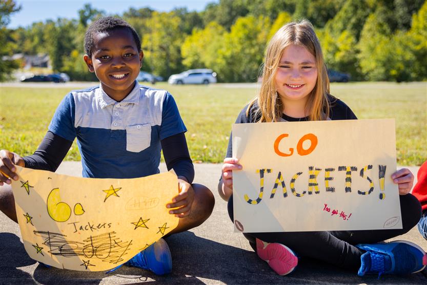 Two elementary students hold up Fairview High signs